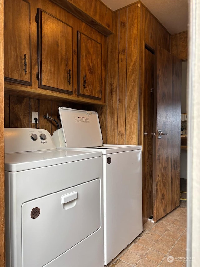 laundry room featuring cabinets, light tile patterned flooring, wooden walls, and independent washer and dryer