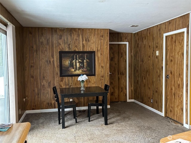 dining room featuring wooden walls and carpet