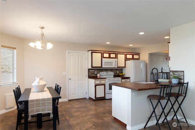 kitchen featuring decorative light fixtures, tasteful backsplash, sink, a notable chandelier, and white appliances