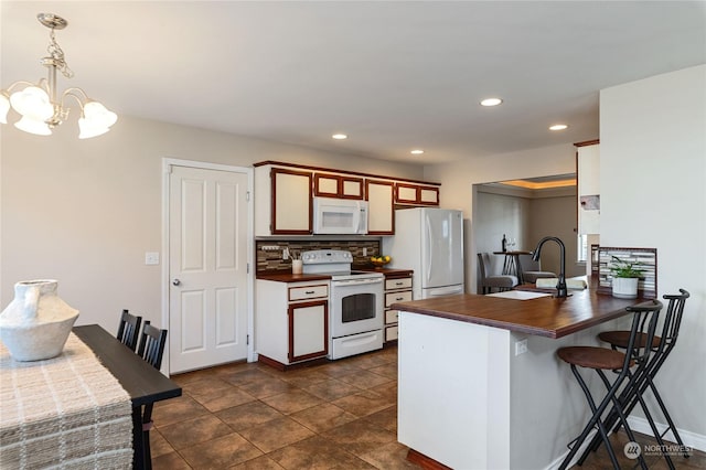 kitchen featuring sink, white appliances, hanging light fixtures, tasteful backsplash, and kitchen peninsula