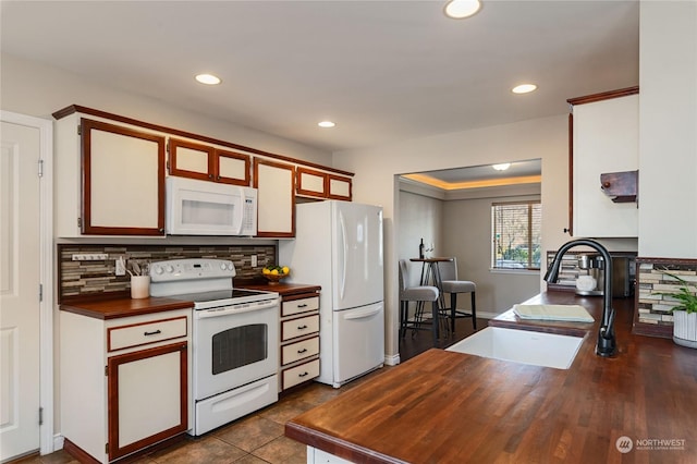 kitchen featuring tasteful backsplash, sink, white cabinets, and white appliances