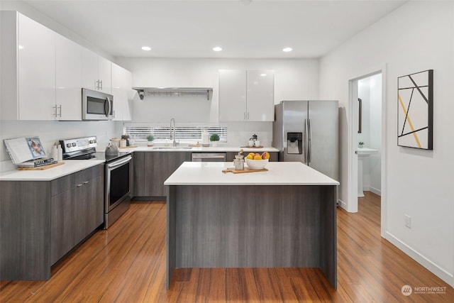 kitchen featuring dark brown cabinetry, sink, white cabinetry, a center island, and stainless steel appliances