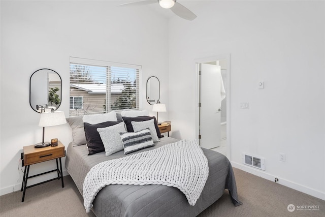 carpeted bedroom featuring ceiling fan and a high ceiling