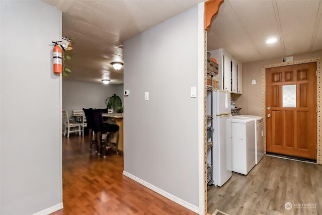 laundry area featuring cabinets, separate washer and dryer, and light hardwood / wood-style floors