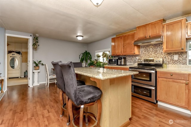 kitchen featuring a breakfast bar area, decorative backsplash, a center island, light hardwood / wood-style floors, and stainless steel appliances