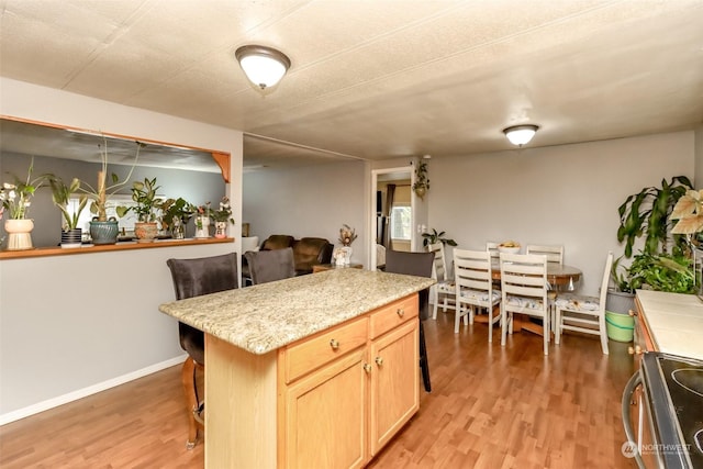 kitchen featuring a center island, light wood-type flooring, light brown cabinetry, and electric stove