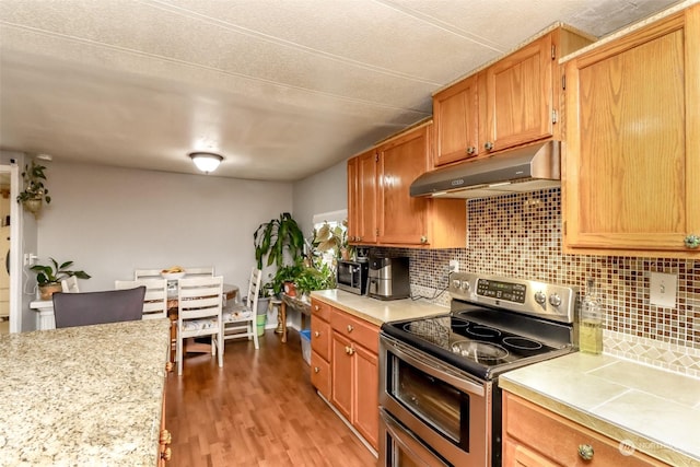 kitchen with wood-type flooring, appliances with stainless steel finishes, and decorative backsplash