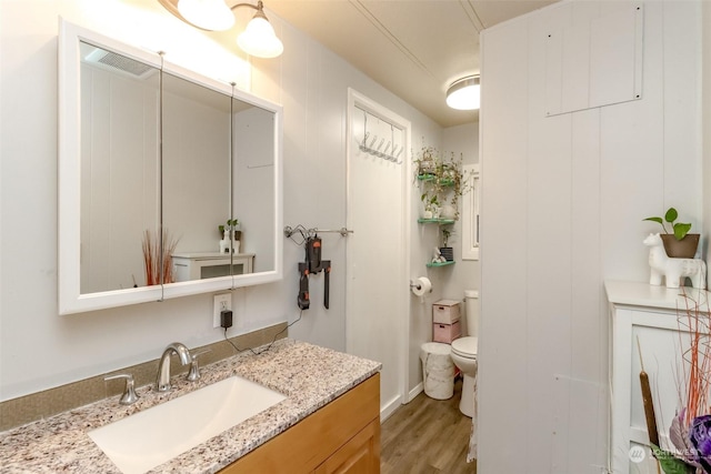 bathroom featuring vanity, wood-type flooring, and toilet