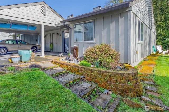 view of front of property with board and batten siding, a chimney, and a front yard