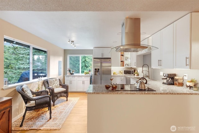 kitchen with a sink, white cabinetry, appliances with stainless steel finishes, a peninsula, and island range hood