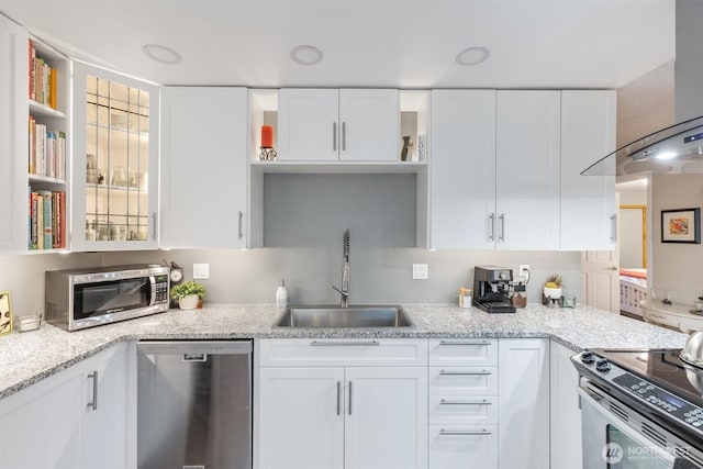 kitchen with light stone counters, open shelves, a sink, appliances with stainless steel finishes, and white cabinetry