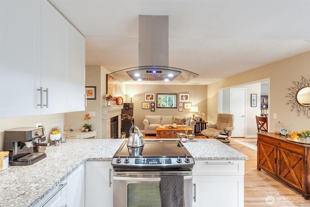 kitchen featuring stainless steel electric range, open floor plan, white cabinetry, light wood-type flooring, and island range hood