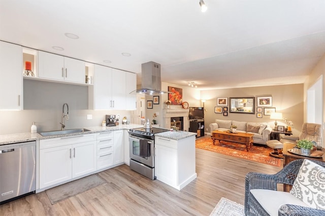 kitchen with a peninsula, a sink, appliances with stainless steel finishes, open floor plan, and island range hood