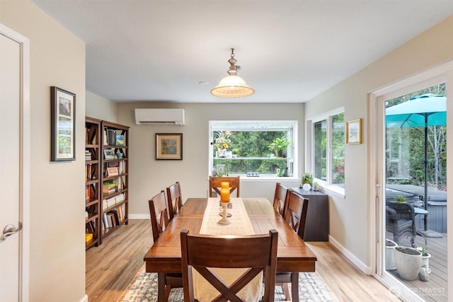 dining room featuring light wood-style flooring, an AC wall unit, and baseboards