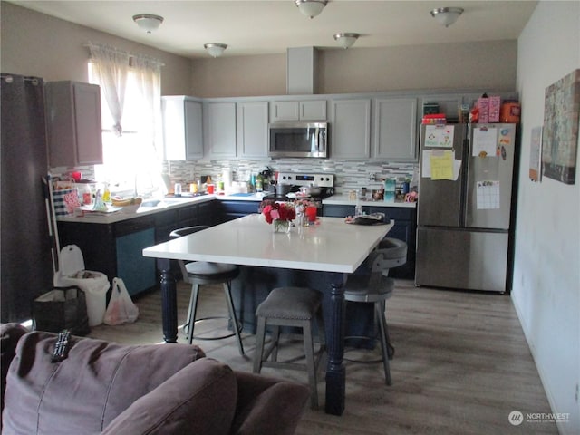 kitchen with tasteful backsplash, appliances with stainless steel finishes, a kitchen bar, and a kitchen island