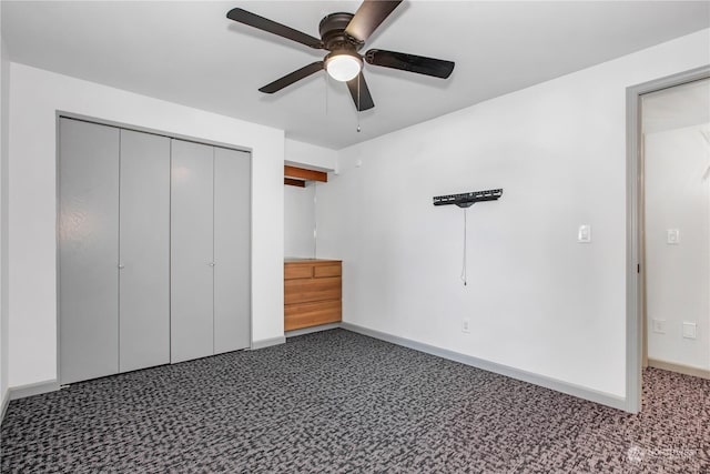 unfurnished bedroom with dark carpet, a closet, and ceiling fan