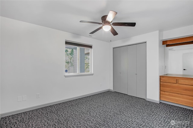 unfurnished bedroom featuring ceiling fan, dark carpet, and a closet