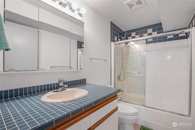 full bathroom featuring enclosed tub / shower combo, vanity, and toilet