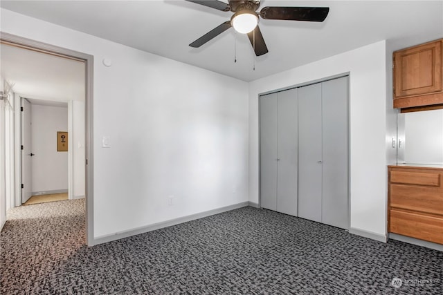 unfurnished bedroom with ceiling fan, dark carpet, and a closet