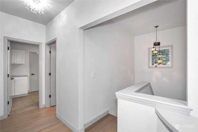 hall featuring an inviting chandelier and light wood-type flooring