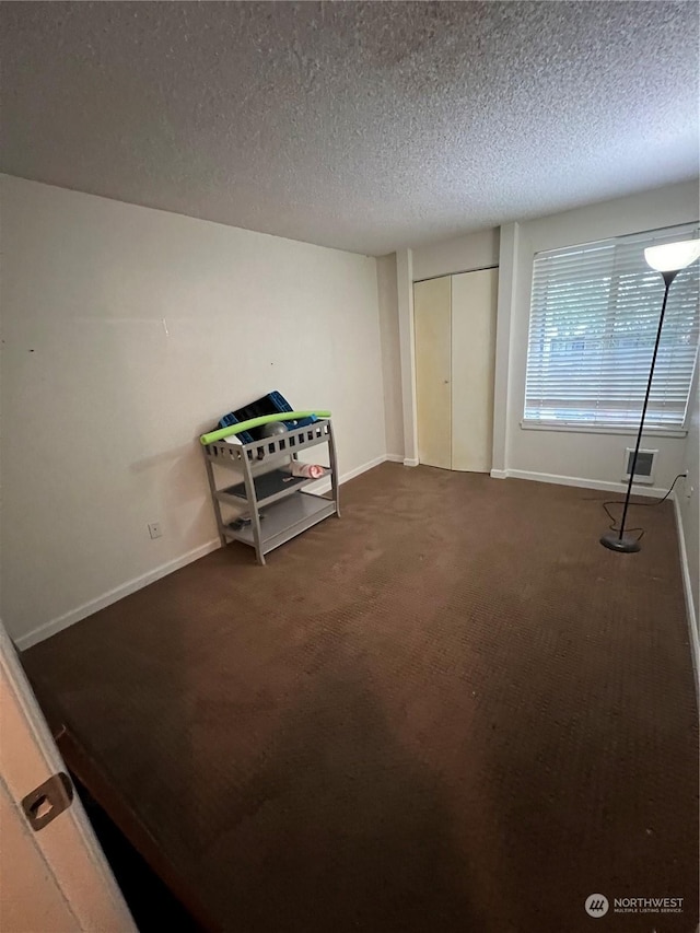 unfurnished bedroom featuring dark carpet and a textured ceiling