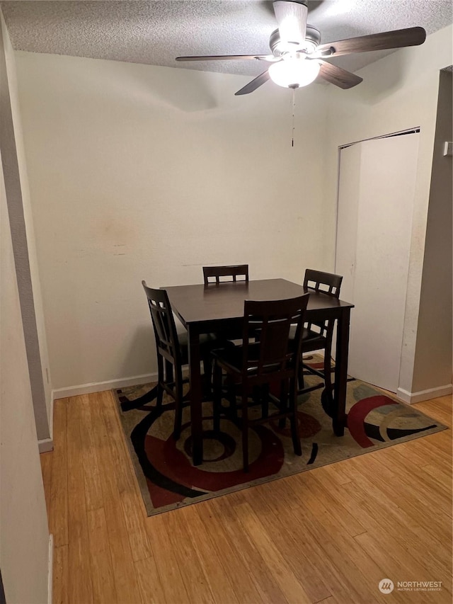 dining room featuring ceiling fan, light hardwood / wood-style floors, and a textured ceiling