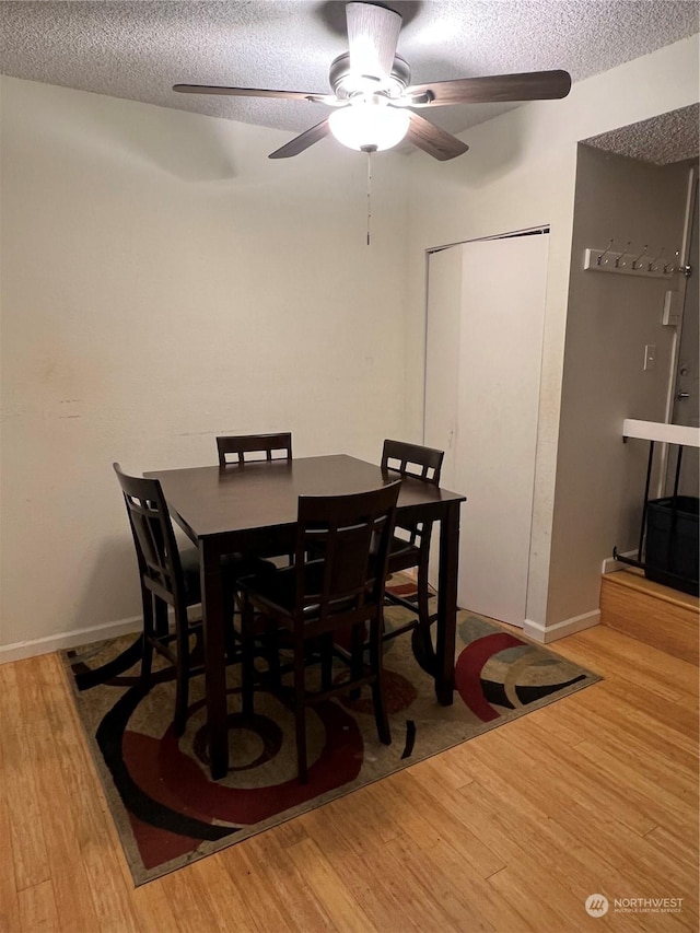 dining space featuring ceiling fan, a textured ceiling, and light wood-type flooring