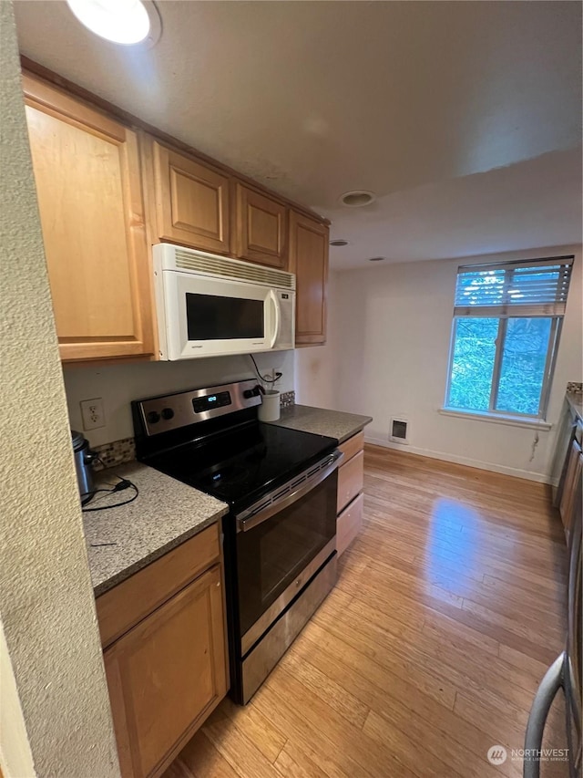 kitchen with stone counters, stainless steel electric range oven, light brown cabinets, and light wood-type flooring