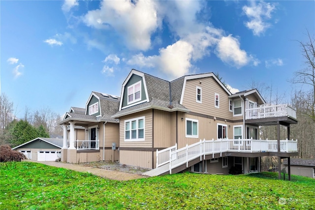 back of property featuring a garage, a wooden deck, an outdoor structure, and a lawn