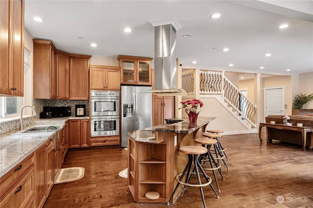 kitchen featuring light stone countertops, island range hood, a breakfast bar area, and stainless steel appliances