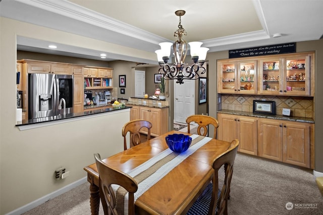 dining area featuring light colored carpet, ornamental molding, a raised ceiling, and a notable chandelier