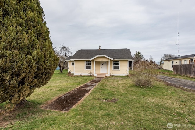 bungalow with a front lawn and fence