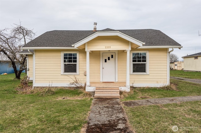 bungalow-style house featuring a shingled roof and a front yard