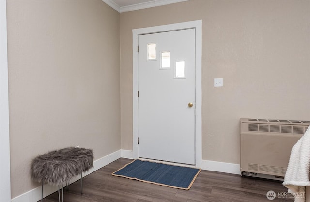 entryway with crown molding, heating unit, wood finished floors, and baseboards