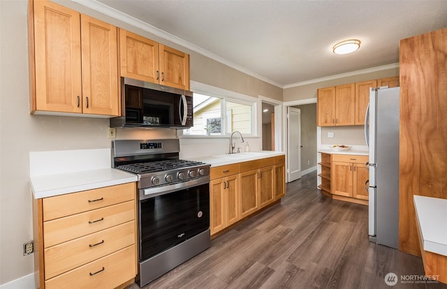 kitchen with dark wood-type flooring, a sink, appliances with stainless steel finishes, crown molding, and light countertops