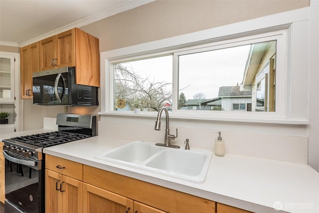 kitchen featuring a sink, stainless steel range with gas stovetop, ornamental molding, and light countertops