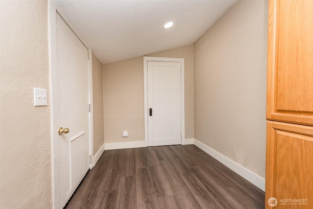 interior space with baseboards, dark wood-style floors, and vaulted ceiling