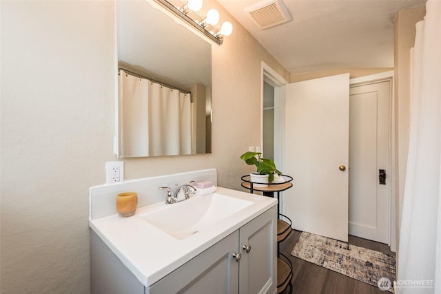 bathroom with visible vents, vanity, and wood finished floors