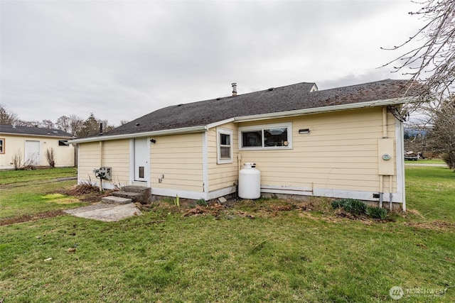 rear view of property with entry steps and a yard