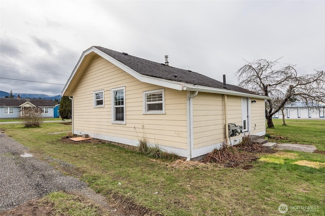 view of home's exterior with a yard and a shingled roof