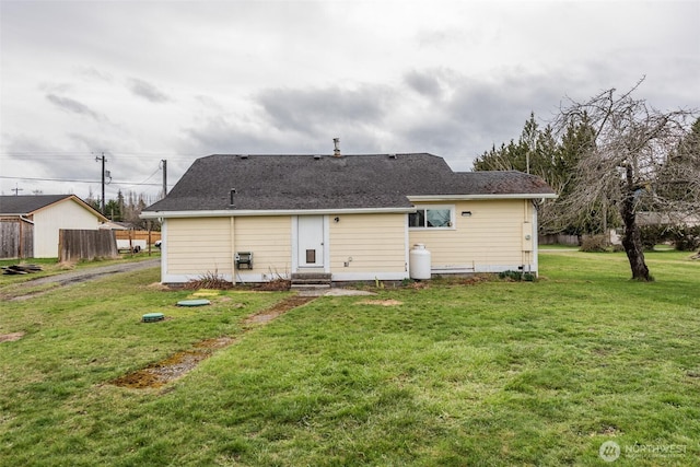 rear view of house with entry steps and a yard