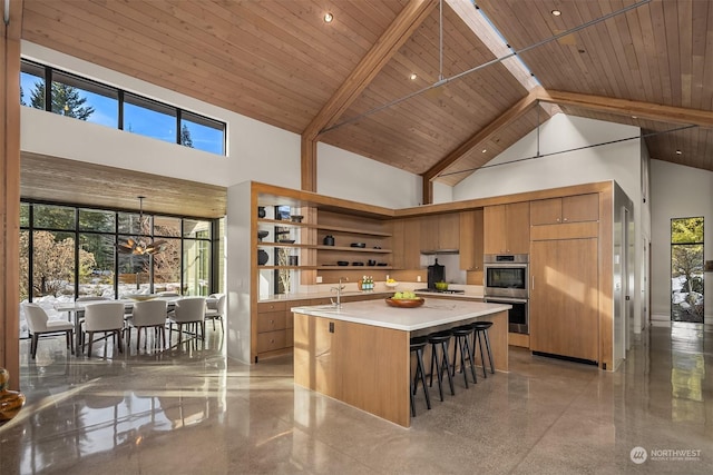 kitchen with a center island, high vaulted ceiling, wooden ceiling, appliances with stainless steel finishes, and a kitchen breakfast bar