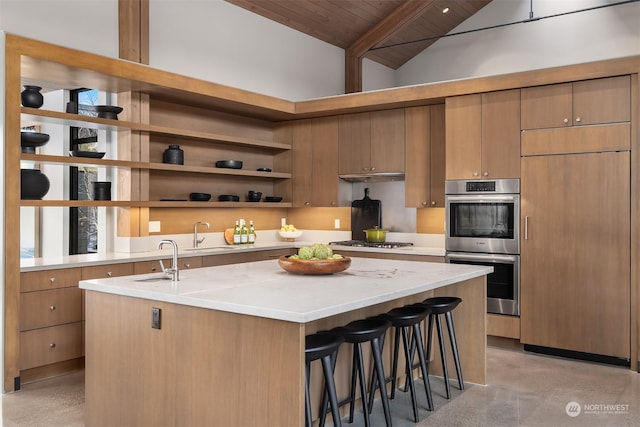 kitchen featuring a breakfast bar, vaulted ceiling with beams, stainless steel appliances, a center island with sink, and wooden ceiling