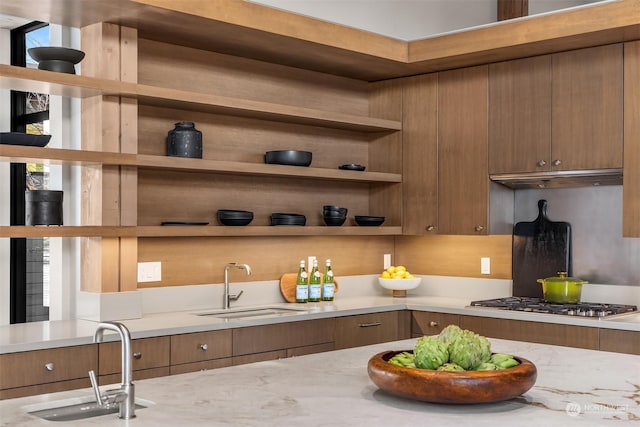 bar featuring stainless steel gas stovetop, light stone countertops, and sink