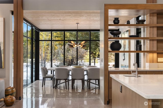 dining area with an inviting chandelier, sink, wood ceiling, and a wall of windows