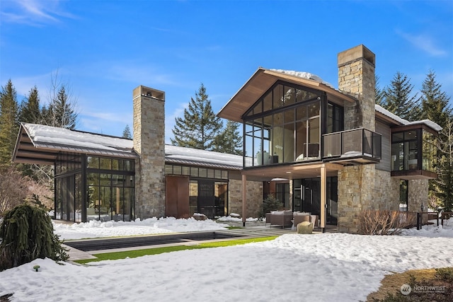 snow covered rear of property featuring a jacuzzi and a sunroom