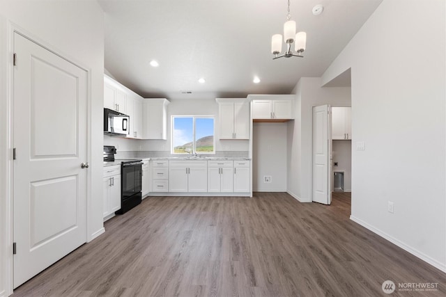 204 Cherry St, Mattawa, WA 99349 - kitchen featuring black appliances, a chandelier, lofted ceiling, light wood-type flooring, and white cabinets