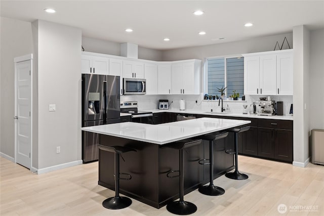 kitchen with appliances with stainless steel finishes, a center island, sink, and white cabinets