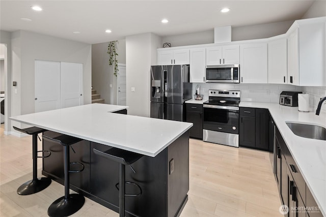 kitchen with a breakfast bar area, appliances with stainless steel finishes, a center island, and sink