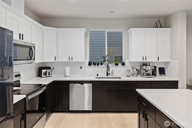 kitchen with white cabinetry, appliances with stainless steel finishes, sink, and decorative backsplash